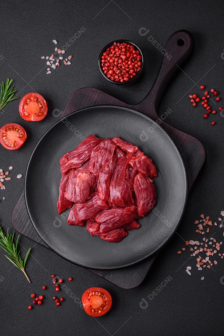 Carne crua fresca com sal, especiarias e ervas sobre um fundo escuro de concreto