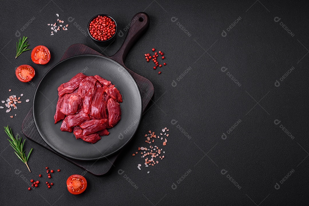 Carne crua fresca com sal, especiarias e ervas sobre um fundo escuro de concreto