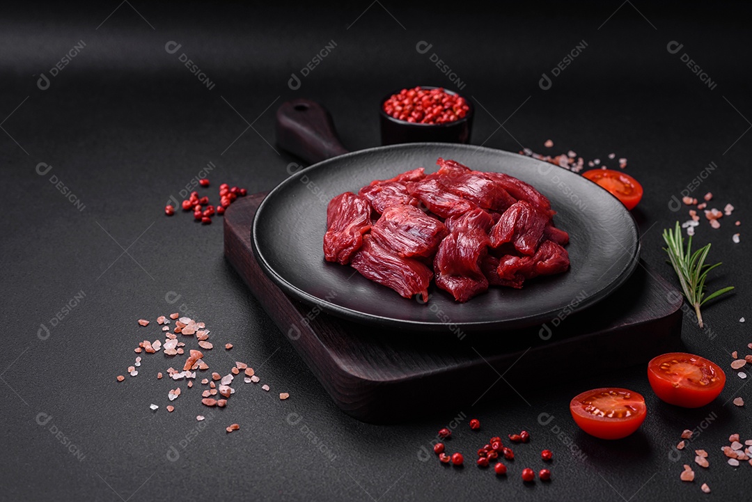 Carne crua fresca com sal, especiarias e ervas sobre um fundo escuro de concreto