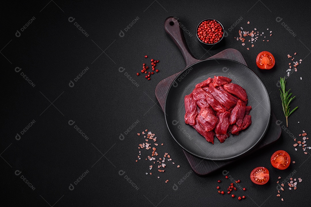 Carne crua fresca com sal, especiarias e ervas sobre um fundo escuro de concreto