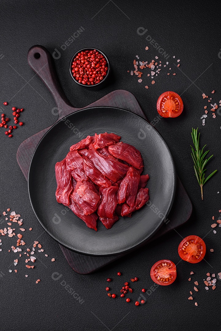 Carne crua fresca com sal, especiarias e ervas sobre um fundo escuro de concreto