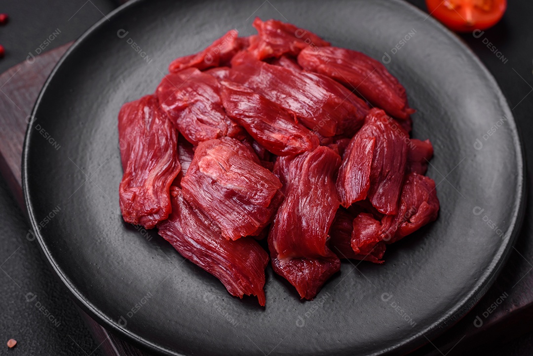 Carne crua fresca com sal, especiarias e ervas sobre um fundo escuro de concreto