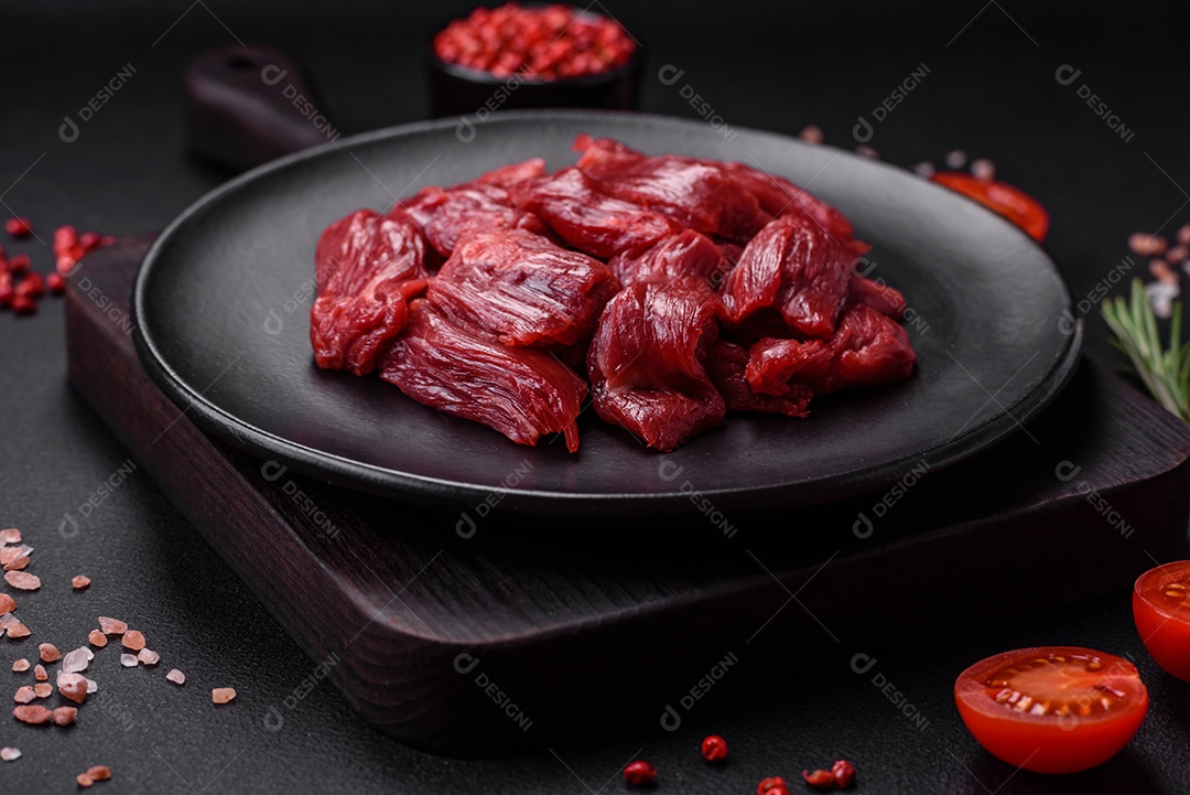 Carne crua fresca com sal, especiarias e ervas sobre um fundo escuro de concreto