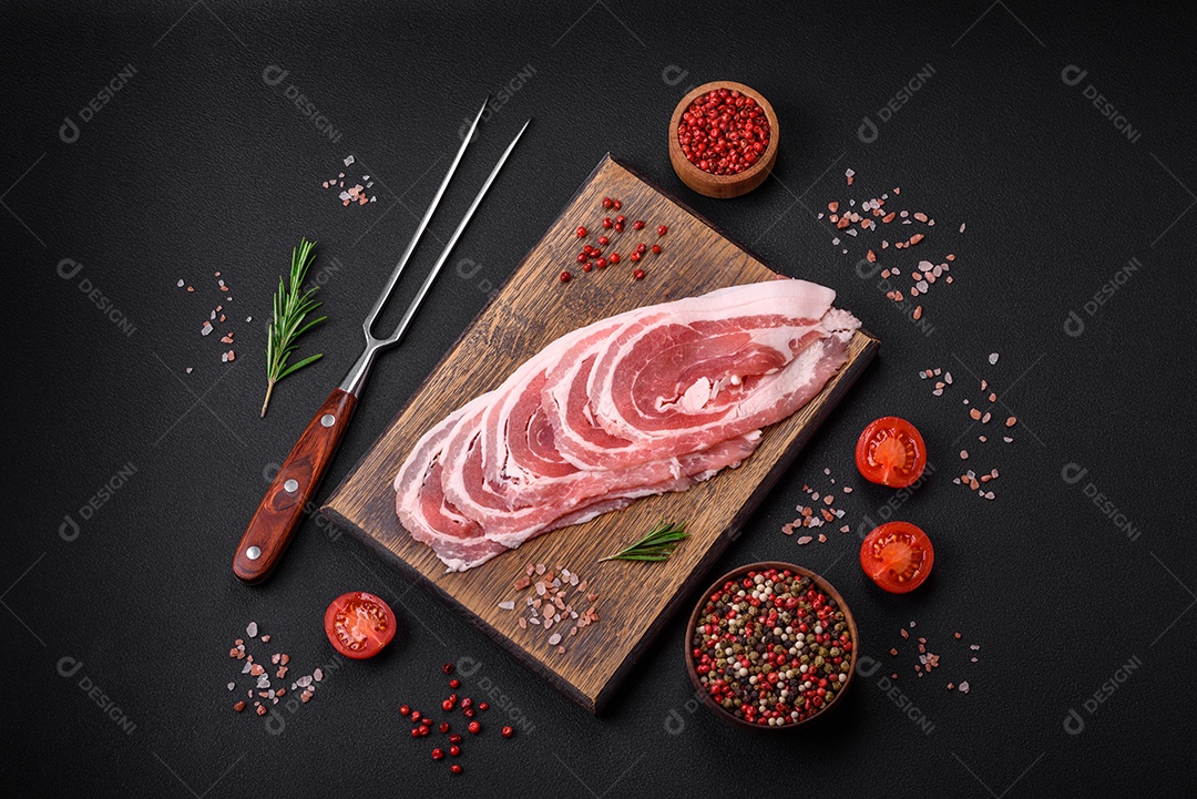 Bacon cru fresco cortado com especiarias e ervas sobre um fundo escuro de concreto