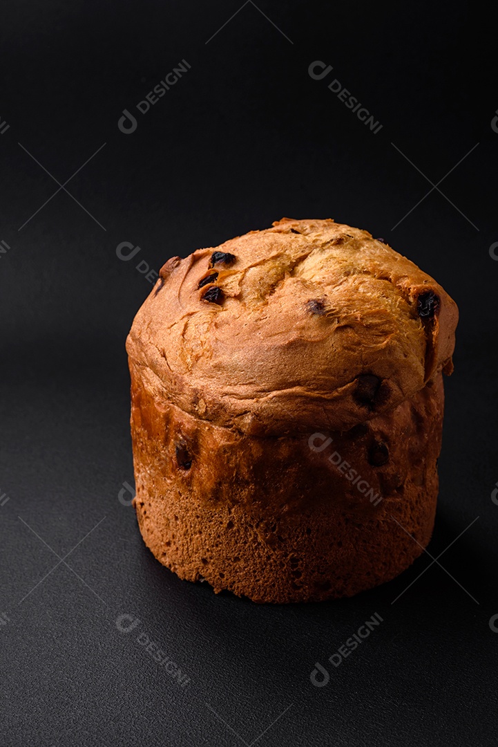 Bolo de Páscoa ou panetone com passas e frutas cristalizadas sobre fundo escuro de concreto