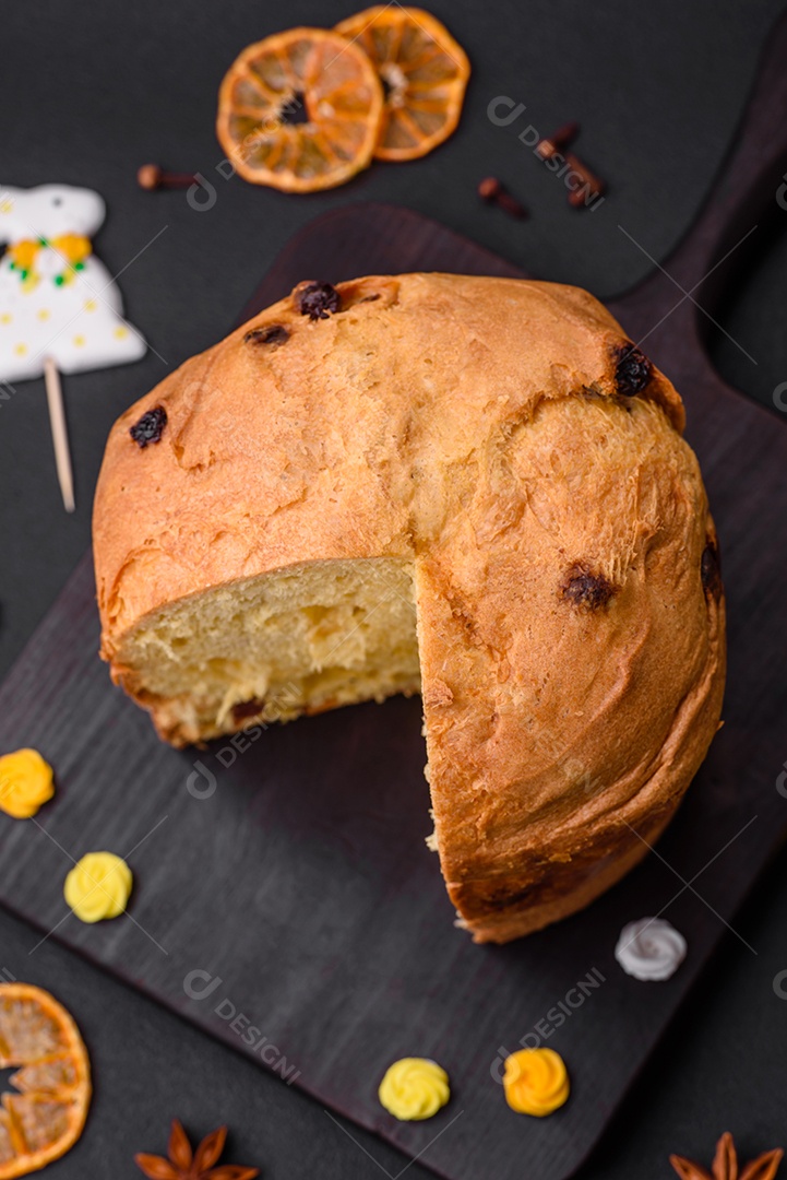 Bolo de Páscoa ou panetone com passas e frutas cristalizadas sobre fundo escuro de concreto