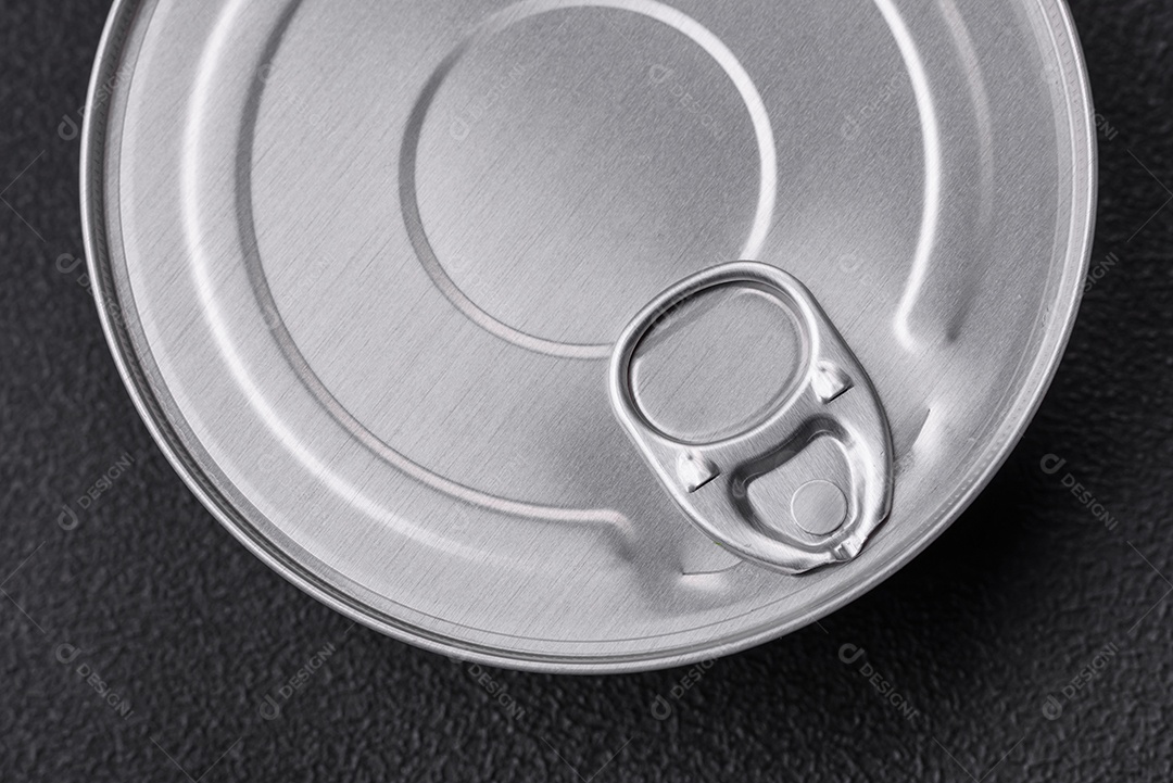 Lata metálica com forma redonda de comida enlatada com uma chave sobre um fundo escuro de concreto