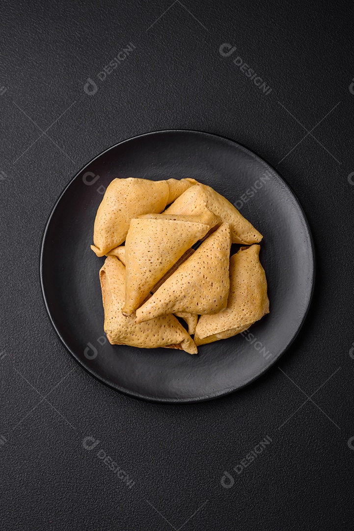 Deliciosas panquecas triangulares com carne, sal e especiarias sobre um fundo escuro de concreto