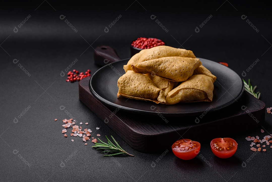 Deliciosas panquecas triangulares com carne, sal e especiarias sobre um fundo escuro de concreto