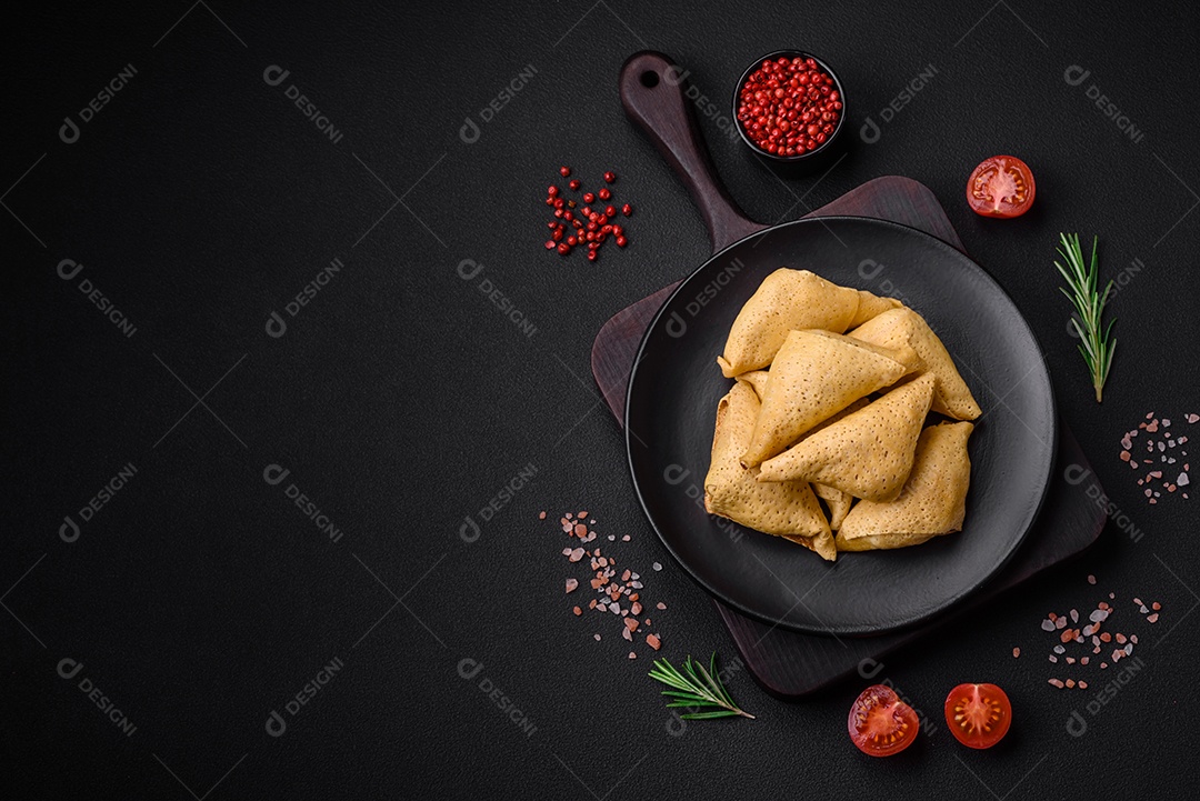 Deliciosas panquecas triangulares com carne, sal e especiarias sobre um fundo escuro de concreto