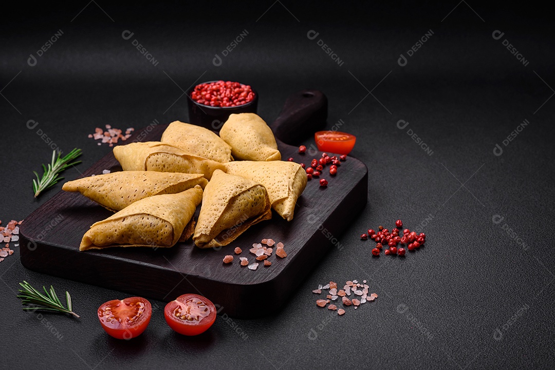 Deliciosas panquecas triangulares com carne, sal e especiarias sobre um fundo escuro de concreto