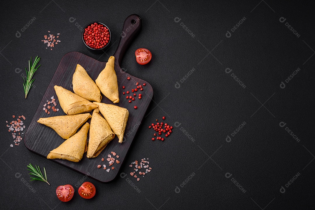 Deliciosas panquecas triangulares com carne, sal e especiarias sobre um fundo escuro de concreto