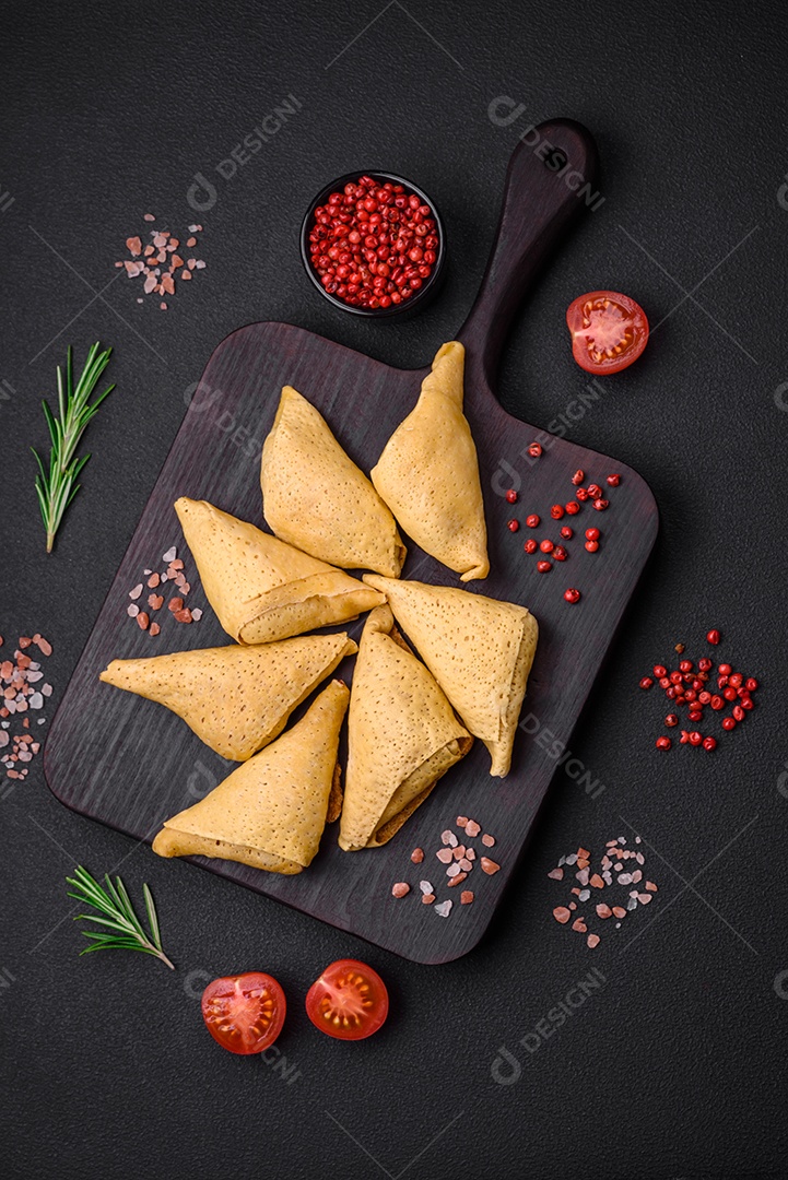 Deliciosas panquecas triangulares com carne, sal e especiarias sobre um fundo escuro de concreto