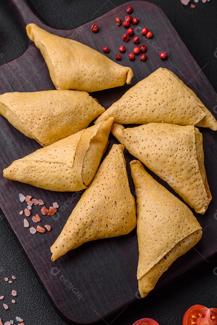 Deliciosas panquecas triangulares com carne, sal e especiarias sobre um fundo escuro de concreto