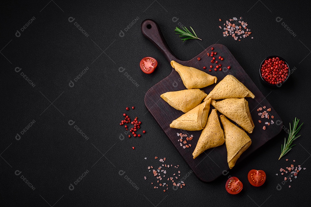 Deliciosas panquecas triangulares com carne, sal e especiarias sobre um fundo escuro de concreto