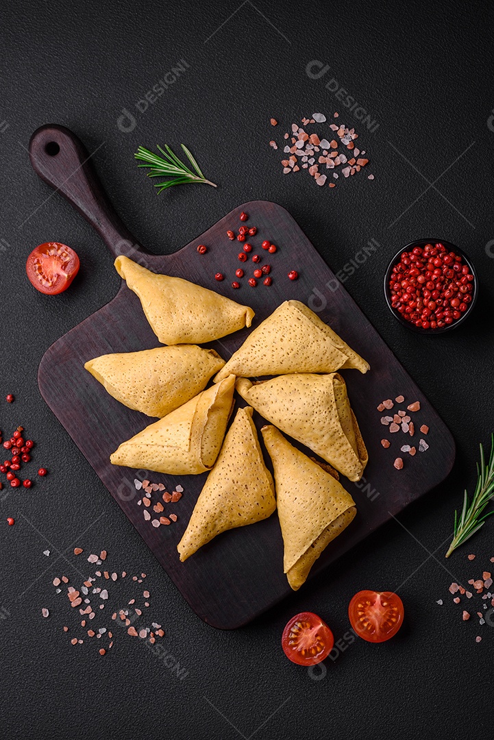 Deliciosas panquecas triangulares com carne, sal e especiarias sobre um fundo escuro de concreto