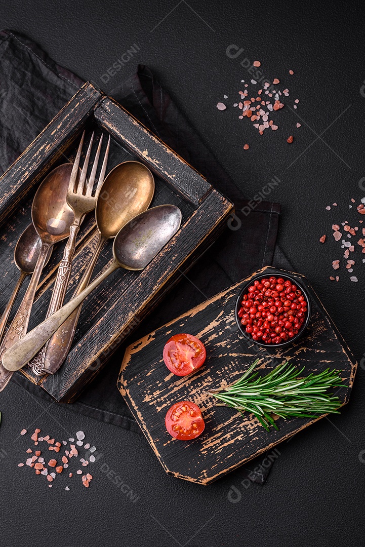 Caixa de madeira retangular vintage com colheres e garfos sobre um fundo escuro de concreto