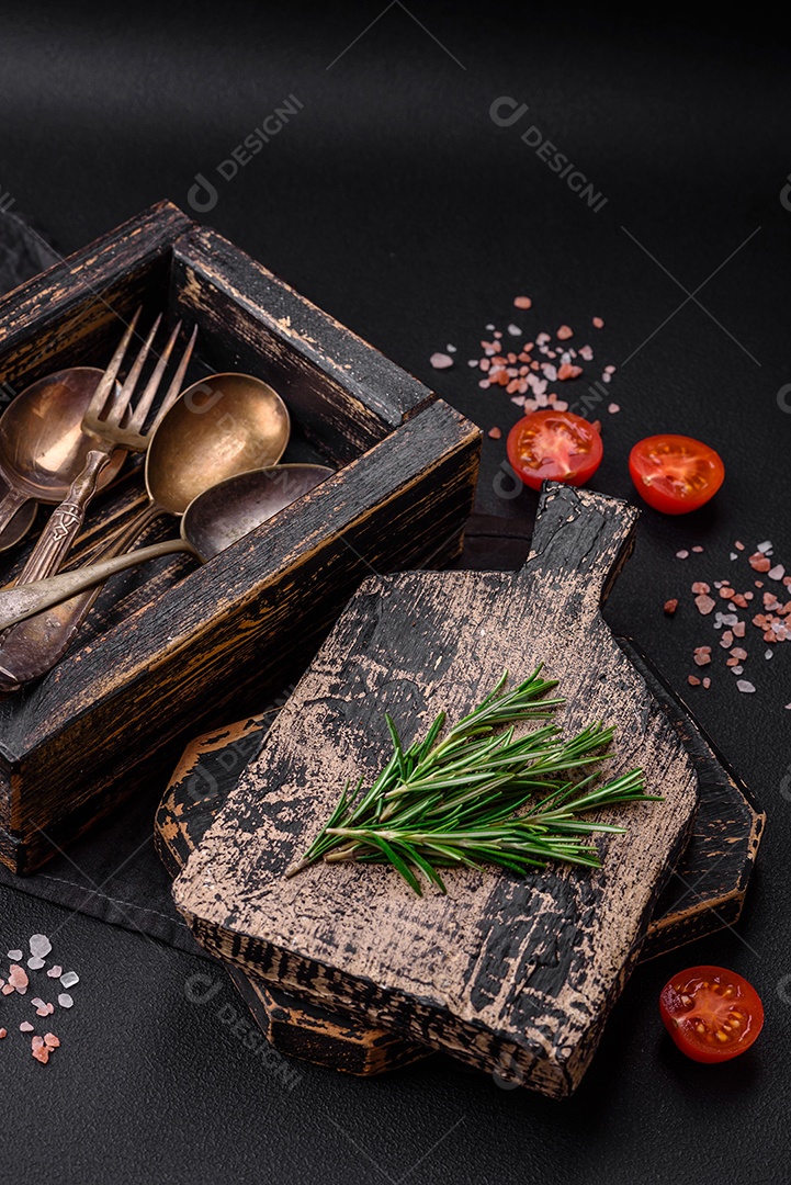 Caixa de madeira retangular vintage com colheres e garfos sobre um fundo escuro de concreto