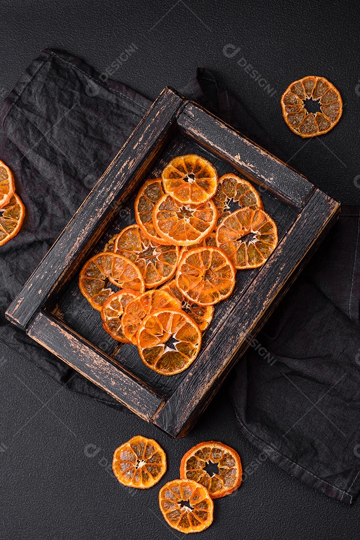Linda decoração de Natal composta por uma velha caixa de madeira com frutas cítricas secas sobre um fundo escuro de concreto