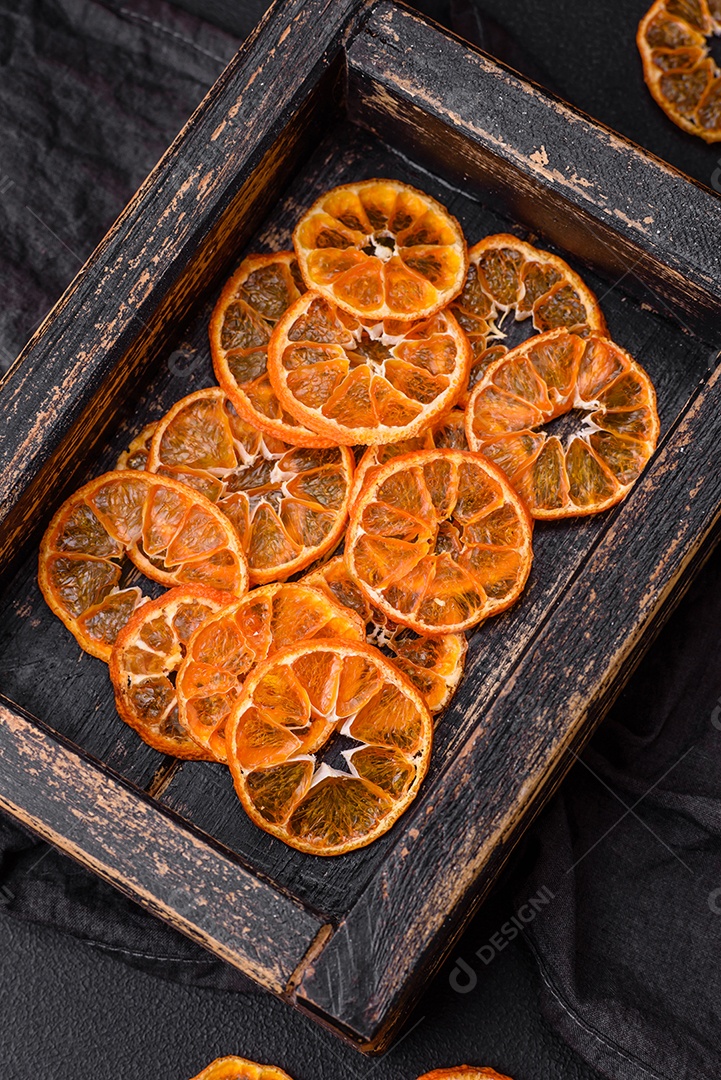 Linda decoração de Natal composta por uma velha caixa de madeira com frutas cítricas secas sobre um fundo escuro de concreto