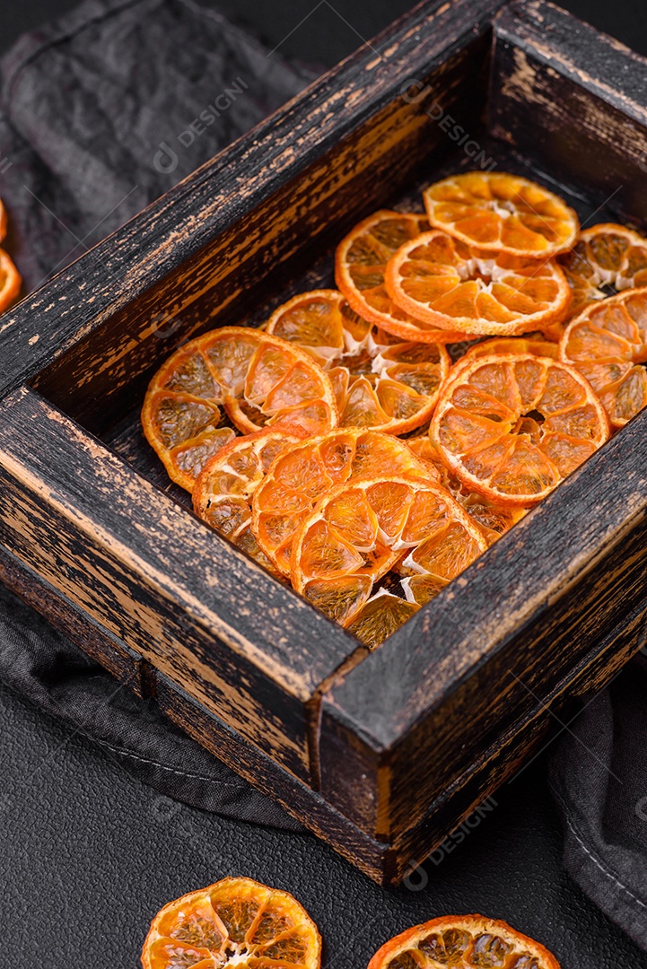 Linda decoração de Natal composta por uma velha caixa de madeira com frutas cítricas secas sobre um fundo escuro de concreto