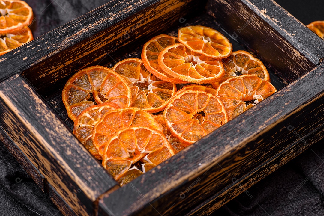 Linda decoração de Natal composta por uma velha caixa de madeira com frutas cítricas secas sobre um fundo escuro de concreto