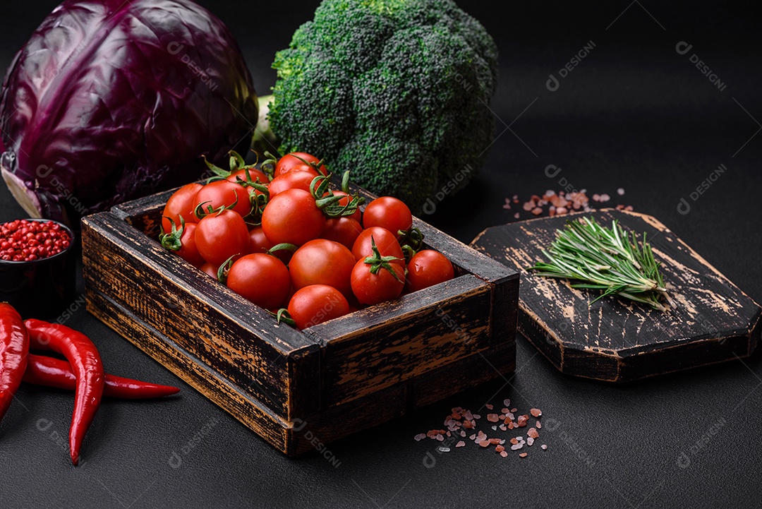 Tomates cereja vermelhos frescos em uma caixa vintage de madeira sobre um fundo escuro de concreto