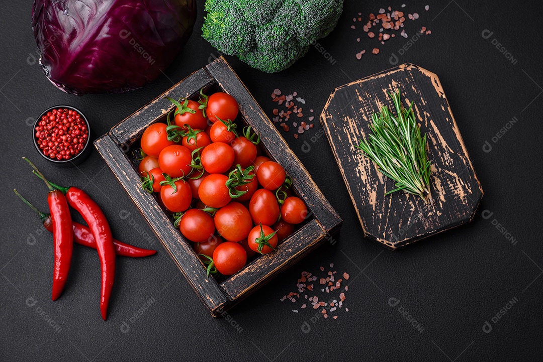 Tomates cereja vermelhos frescos em uma caixa vintage de madeira sobre um fundo escuro de concreto