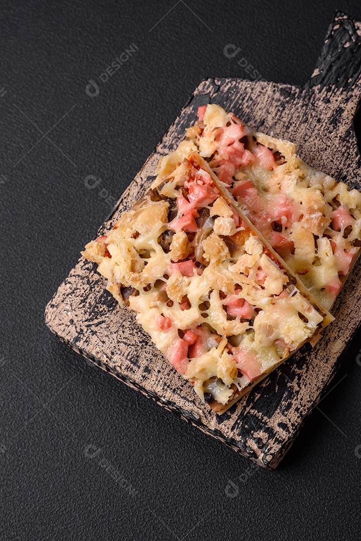 Deliciosa pizza caseira com salsicha, cogumelos e queijo cortados em pedaços sobre um fundo escuro de concreto