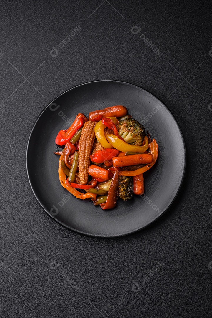 Legumes deliciosos pimentões cozidos no vapor, feijão de espargos e batatas fatiadas com molho de soja sobre um fundo escuro de concreto