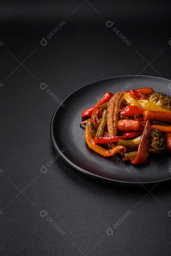 Legumes deliciosos pimentões cozidos no vapor, feijão de espargos e batatas fatiadas com molho de soja sobre um fundo escuro de concreto