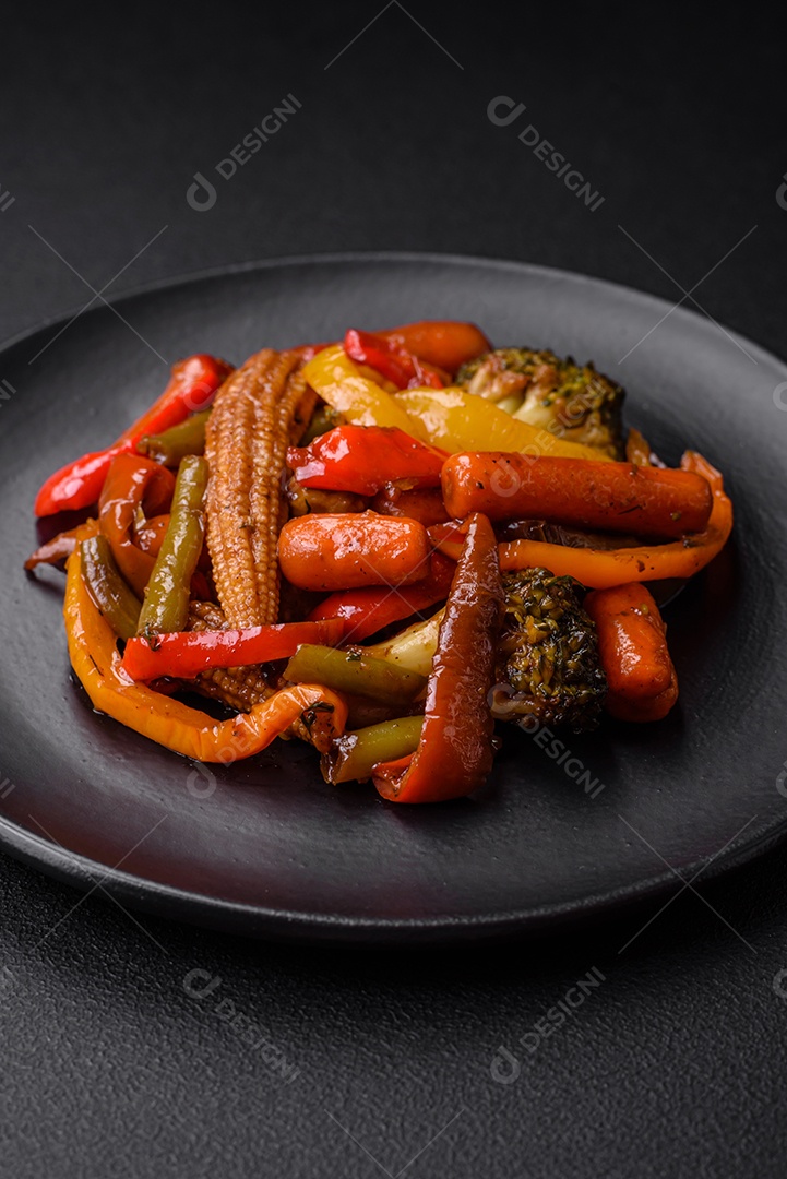 Legumes deliciosos pimentões cozidos no vapor, feijão de espargos e batatas fatiadas com molho de soja sobre um fundo escuro de concreto