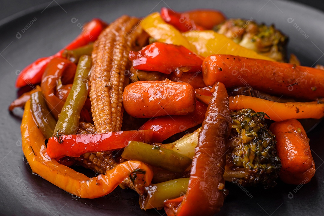 Legumes deliciosos pimentões cozidos no vapor, feijão de espargos e batatas fatiadas com molho de soja sobre um fundo escuro de concreto