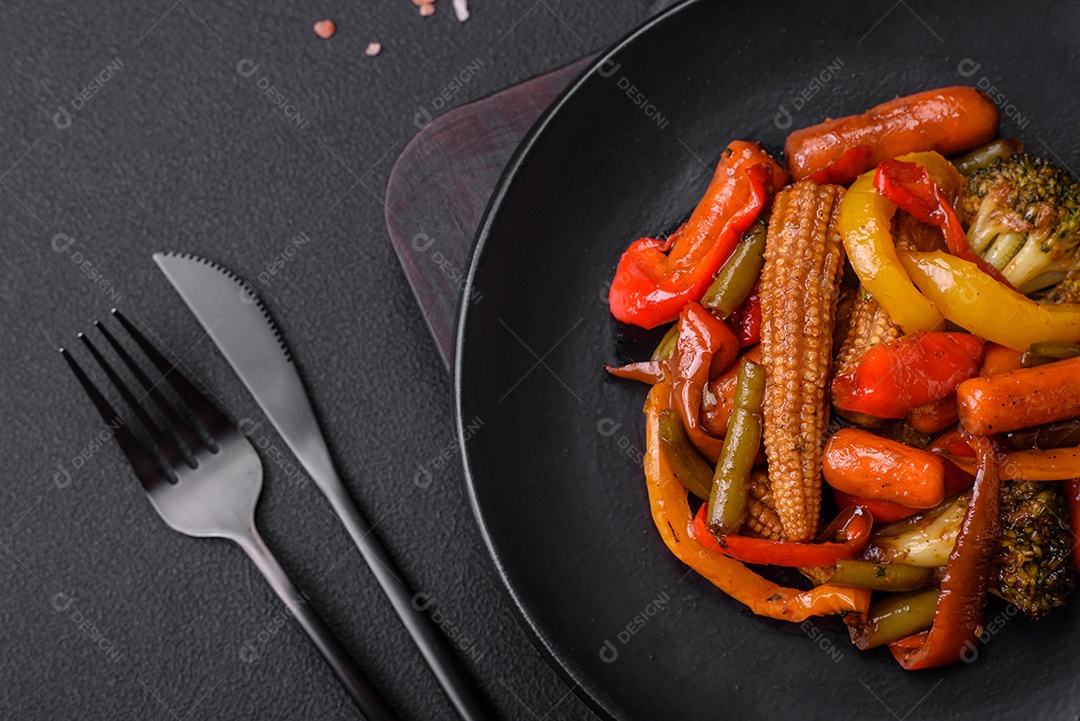 Legumes deliciosos pimentões cozidos no vapor, feijão de espargos e batatas fatiadas com molho de soja sobre um fundo escuro de concreto