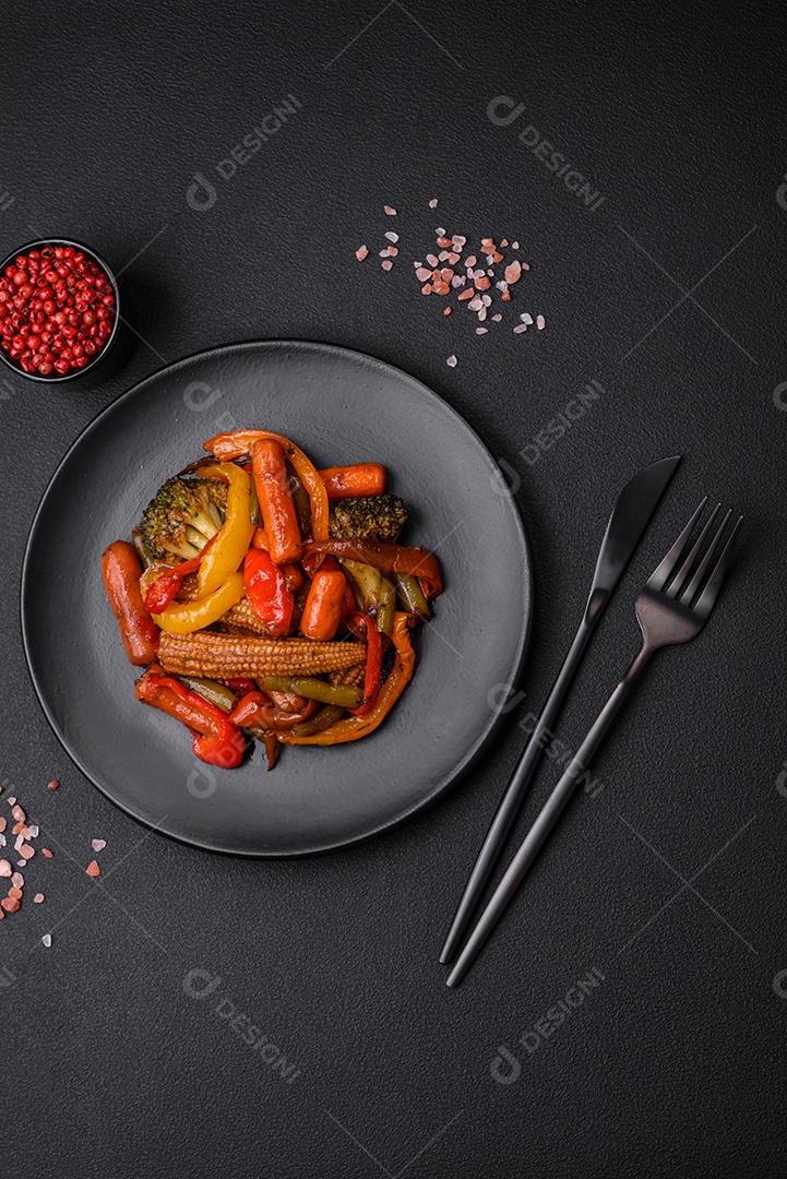 Legumes deliciosos pimentões cozidos no vapor, feijão de espargos e batatas fatiadas com molho de soja sobre um fundo escuro de concreto