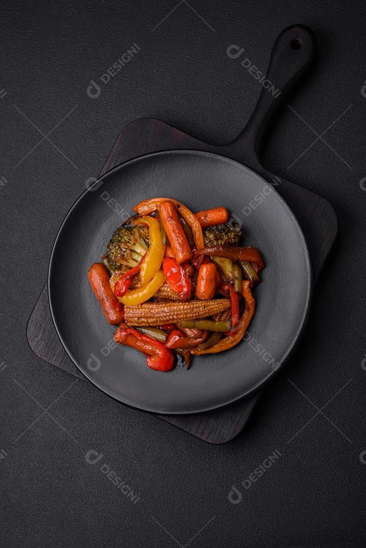 Legumes deliciosos pimentões cozidos no vapor, feijão de espargos e batatas fatiadas com molho de soja sobre um fundo escuro de concreto