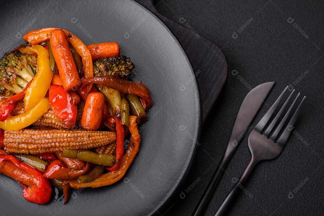 Legumes deliciosos pimentões cozidos no vapor, feijão de espargos e batatas fatiadas com molho de soja sobre um fundo escuro de concreto