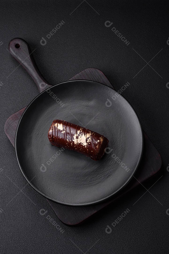Delicioso queijo doce com calda coberta com chocolate e nozes em uma placa de cerâmica sobre um fundo escuro de concreto