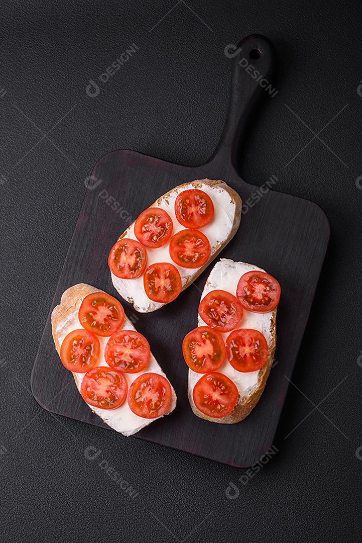 Deliciosa torrada grelhada crocante com queijo e tomate cereja em um fundo escuro de concreto