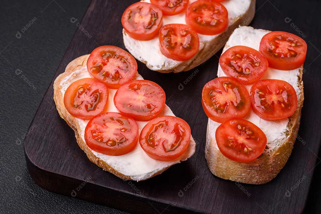 Deliciosa torrada grelhada crocante com queijo e tomate cereja em um fundo escuro de concreto