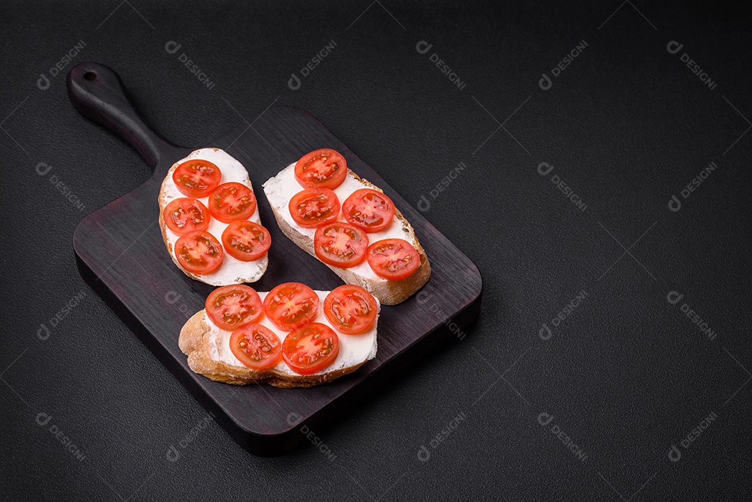 Deliciosa torrada grelhada crocante com queijo e tomate cereja em um fundo escuro de concreto