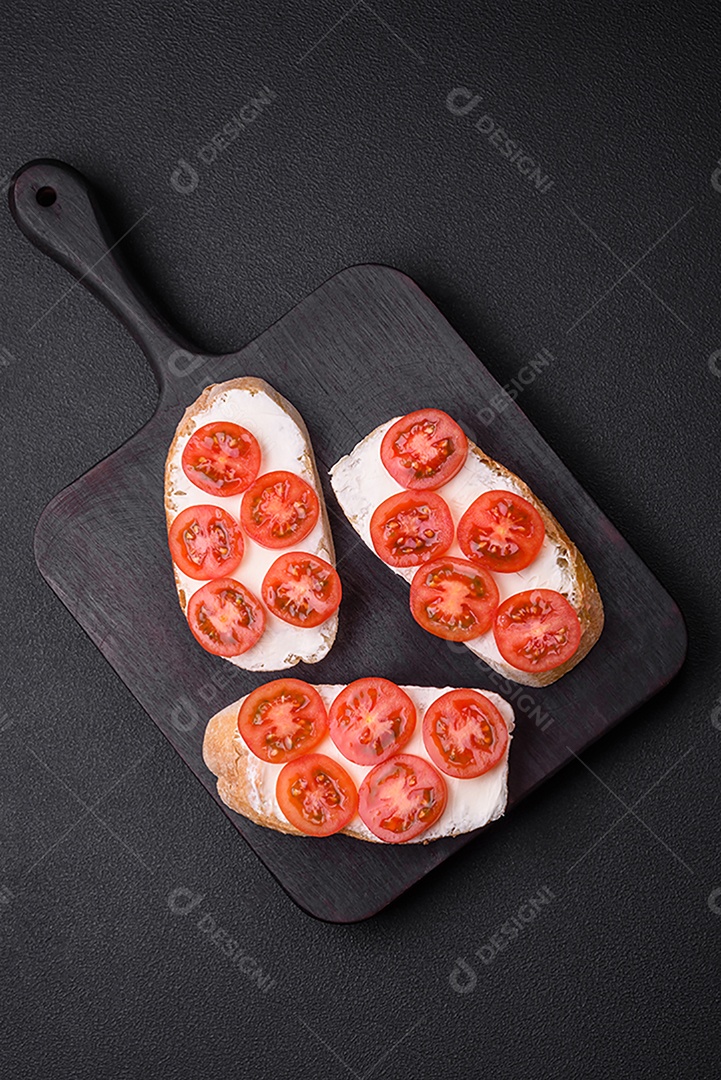 Deliciosa torrada grelhada crocante com queijo e tomate cereja em um fundo escuro de concreto