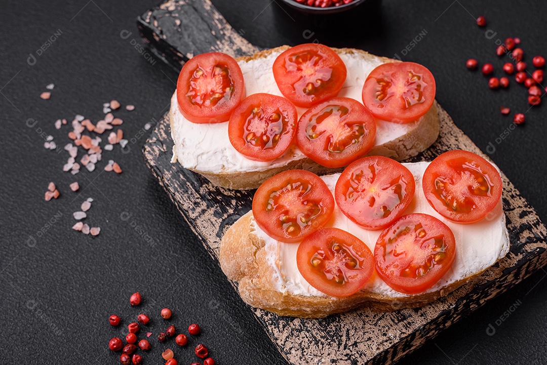 Deliciosa torrada grelhada crocante com queijo e tomate cereja em um fundo escuro de concreto
