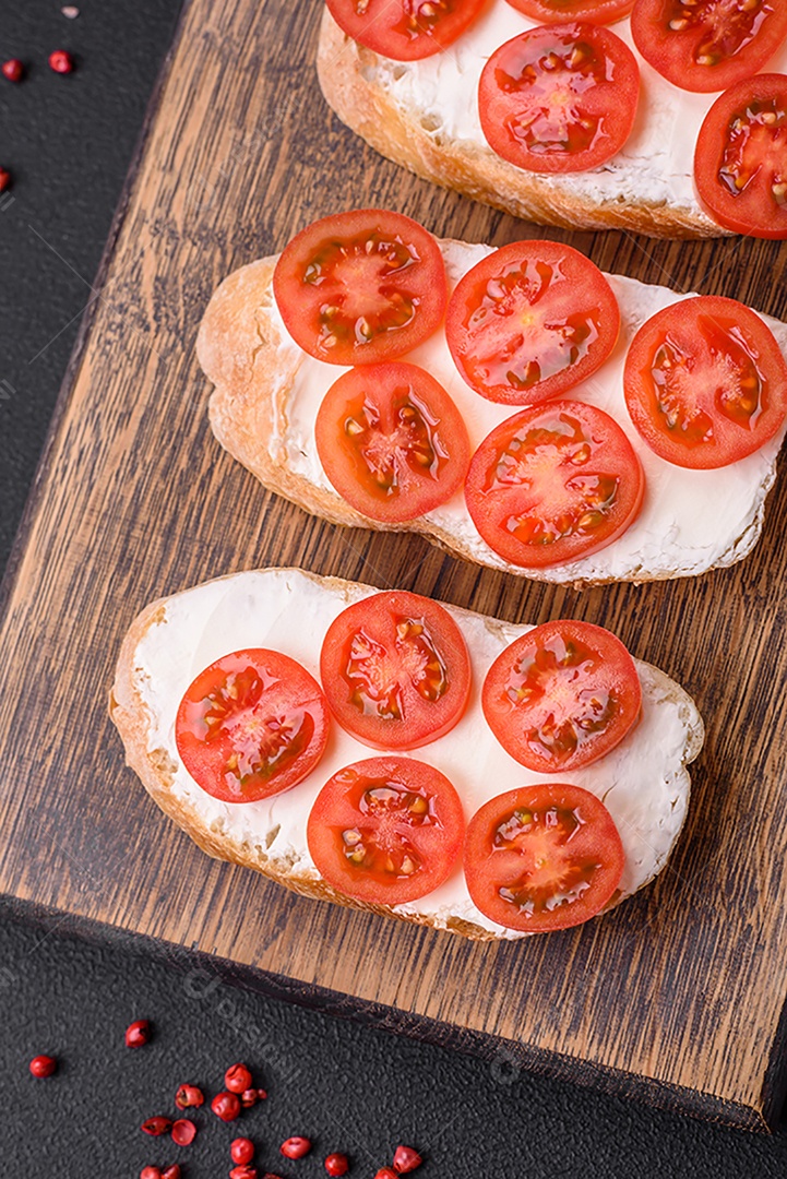 Deliciosa torrada grelhada crocante com queijo e tomate cereja em um fundo escuro de concreto