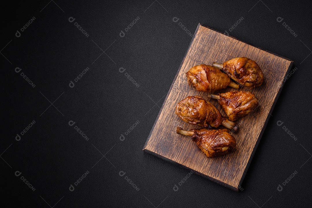 Deliciosas pernas de frango grelhado com especiarias e ervas em molho teriyaki sobre um fundo escuro de concreto