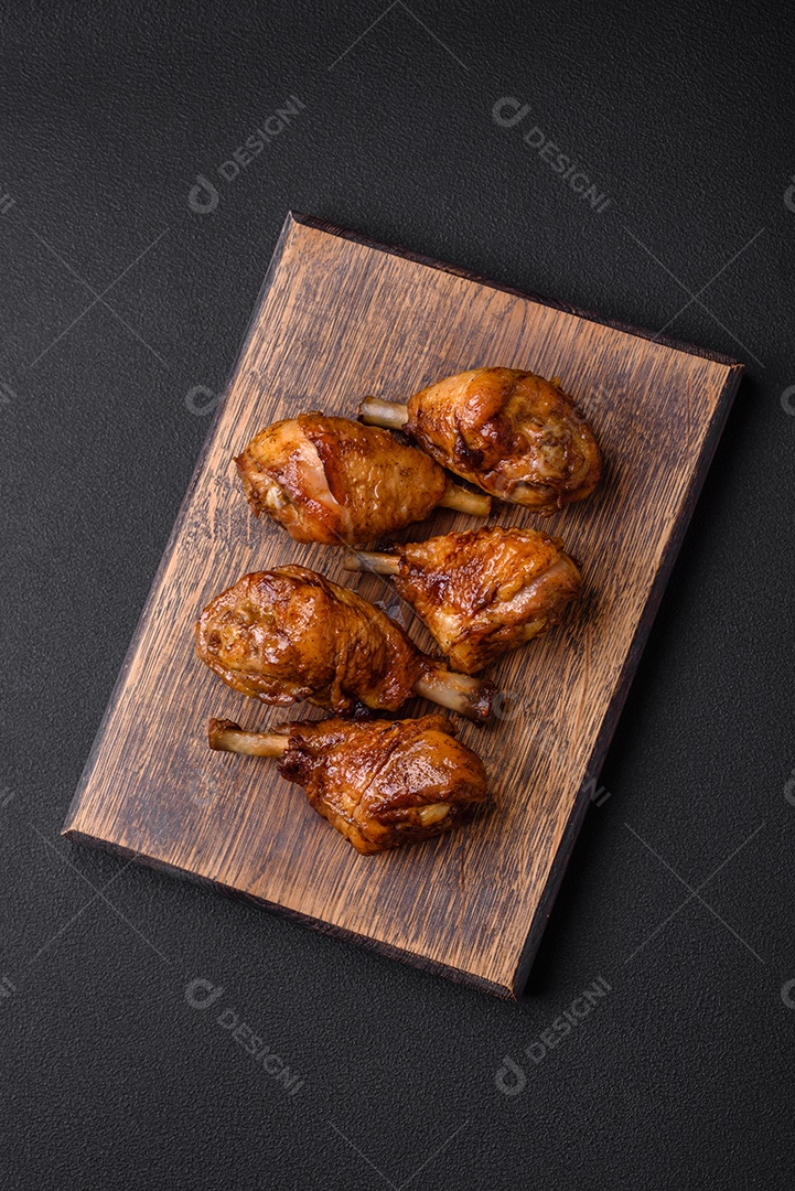 Deliciosas pernas de frango grelhado com especiarias e ervas em molho teriyaki sobre um fundo escuro de concreto