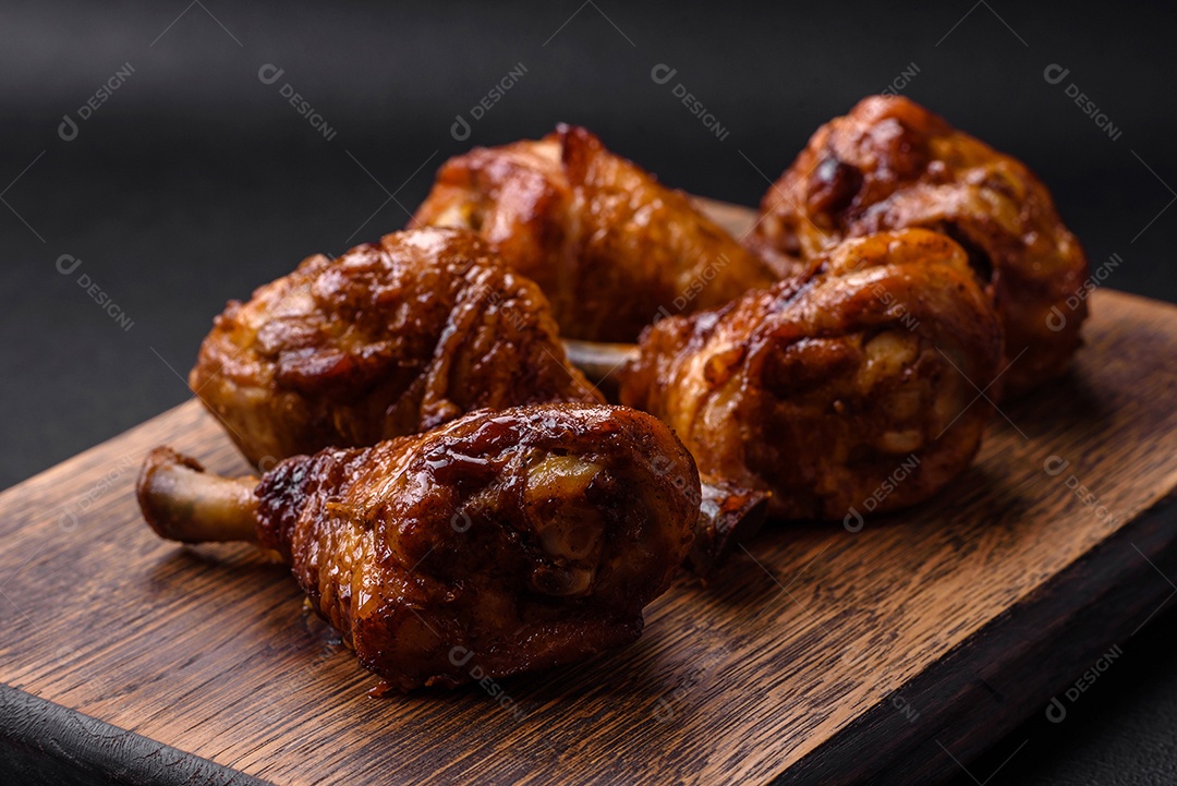 Deliciosas pernas de frango grelhado com especiarias e ervas em molho teriyaki sobre um fundo escuro de concreto