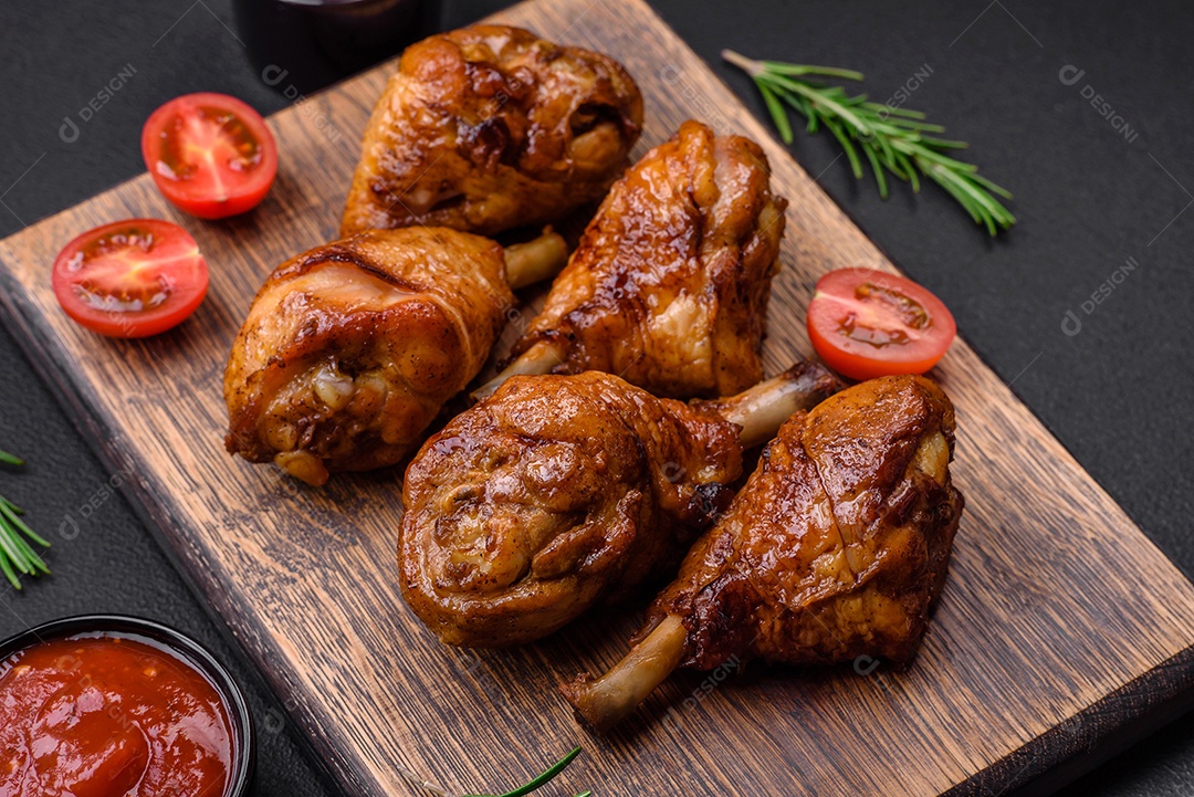 Deliciosas pernas de frango grelhado com especiarias e ervas em molho teriyaki sobre um fundo escuro de concreto