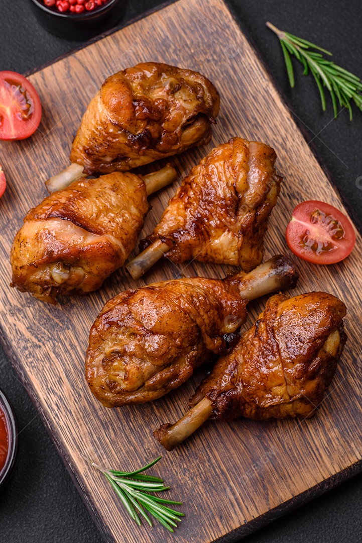 Deliciosas pernas de frango grelhado com especiarias e ervas em molho teriyaki sobre um fundo escuro de concreto