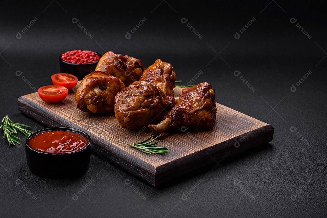 Deliciosas pernas de frango grelhado com especiarias e ervas em molho teriyaki sobre um fundo escuro de concreto